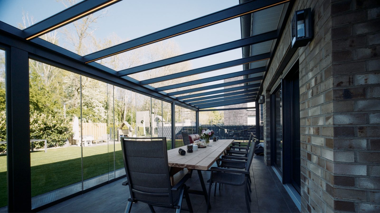 Verglaste Terrassenüberdachung mit Essbereich und Blick in den Garten